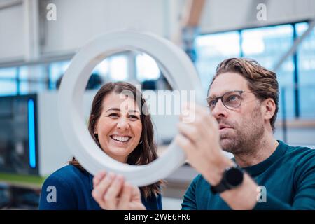 Happy businesswoman analyzing machine part with colleague in industry Stock Photo