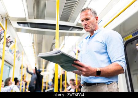 Mature businessman reading newspaper on train Stock Photo