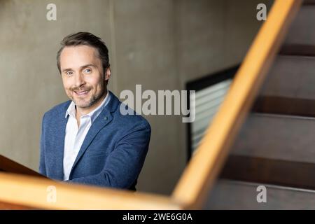 Smiling mature businessman wearing blazer by staircase Stock Photo