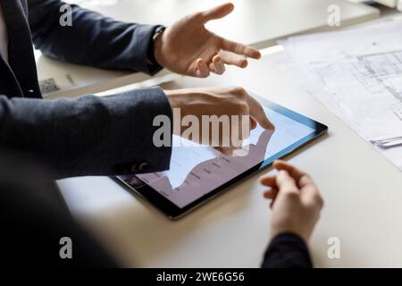 Hand of businessman using tablet computer by trainee at desk in office Stock Photo