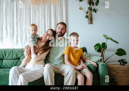 Portrait of family with two sons sitting on the couch in living room Stock Photo