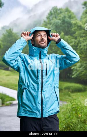 Smiling man wearing blue jacket and standing in front of trees Stock Photo