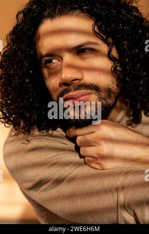 Thoughtful man with black hair and beard leaning on hand Stock Photo