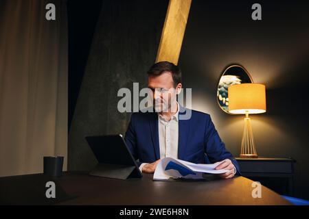 Smiling mature businessman analyzing data and using tablet PC in conference room Stock Photo