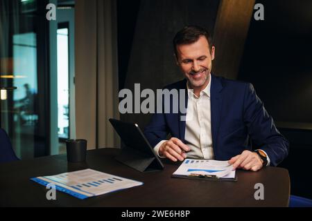 Happy mature businessman analyzing data in conference room Stock Photo