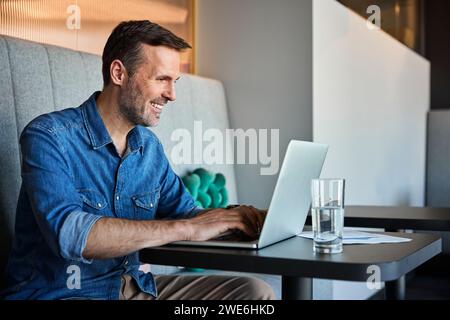Happy mature businessman using laptop at table Stock Photo
