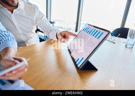 Businessman explaining and discussing over graph with colleague at desk Stock Photo