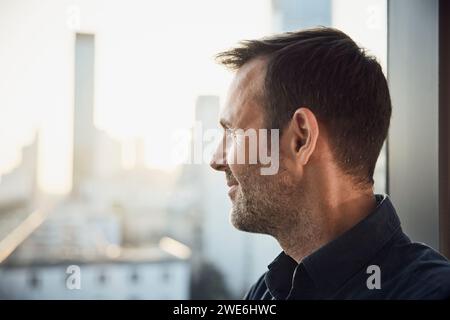 Thoughtful businessman looking through office window Stock Photo