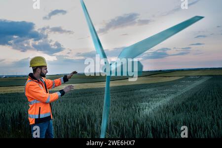 Maintenance engineer working near digital wind turbine in field Stock Photo