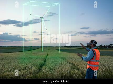 Engineer examining digital wind turbine model through VR glasses in field Stock Photo
