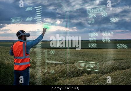 Engineer programming digital wind turbine model through VR glasses in field Stock Photo