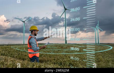 Engineer wearing hardhat and programming digital wind turbine through tablet PC in field Stock Photo