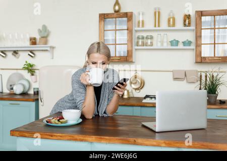Young woman having coffee and using smart phone at home Stock Photo