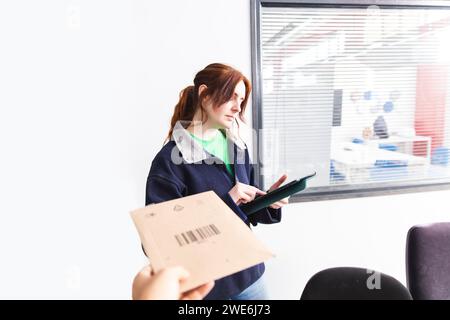 Delivery woman using tablet PC with customer holding package Stock Photo