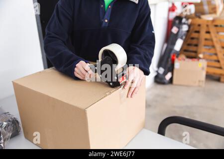 Delivery woman sealing package with tape Stock Photo
