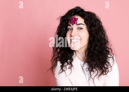 Happy young woman with tied bow on forehead against pink background Stock Photo