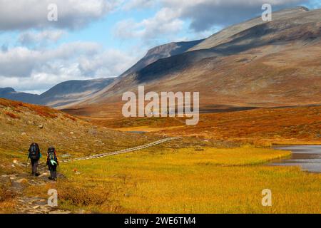 Two hikers walking toward Salka Mountain Hut on Kungsleden trail, Lapland, Sweden Stock Photo