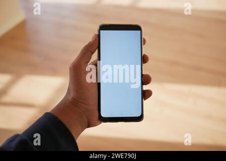pov shot of hand using phone showing empty screen in empty room Stock Photo