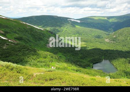 A beautiful small lake in an intermountain valley with remains of snow on the slopes. Ivanovskie lakes, Khakassia, Siberia, Russia. Stock Photo