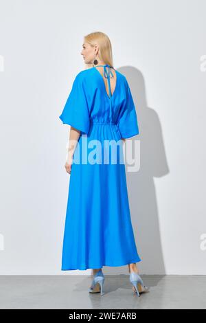 Back view of blonde woman in vibrant long blue dress Stock Photo