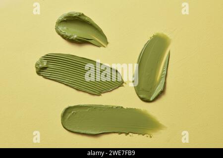 Several green cosmetic smears of green tea clay mask over the pastel background. Hygiene, skin care product creamy texture Stock Photo