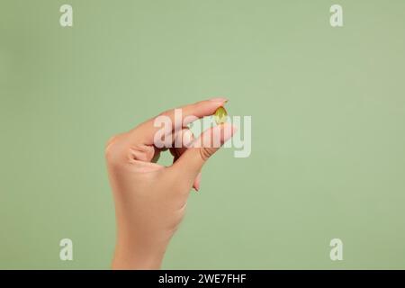 A hand holding a fish oil capsule. Fish oil is one of the most commonly consumed dietary supplements. Rich in omega-3 fatty acids Stock Photo