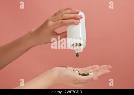 Many capsules are poured from a medicine bottle in white color into a hand. Taking pills or antibiotics, treating various diseases Stock Photo