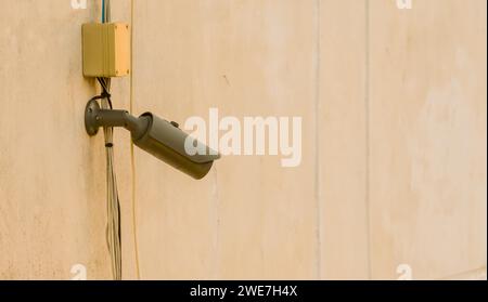 CCTV security camera and associated wires mounted under window on side of dirty concrete building Stock Photo