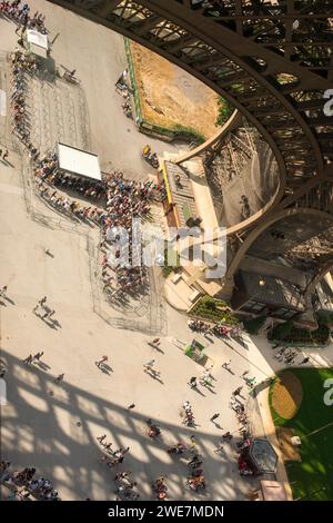 Top view of visitors standing in a queue under the Eiffel Tower, visitors, crowd, architecture of the Eiffel Tower, shadow, sunny day in summer Stock Photo
