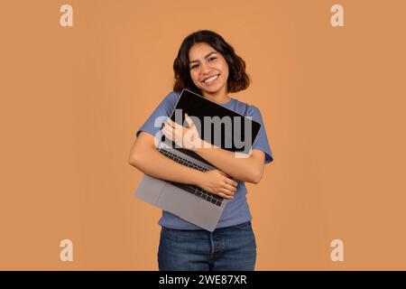 Overjoyed young middle eastern woman hugging her laptop Stock Photo
