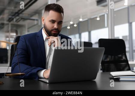 Serious lawyer working with laptop at table in office Stock Photo