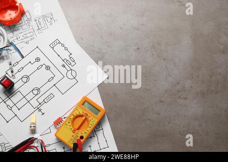 Wiring diagrams, digital multimeter and other electrician's equipment on grey table, flat lay. Space for text Stock Photo