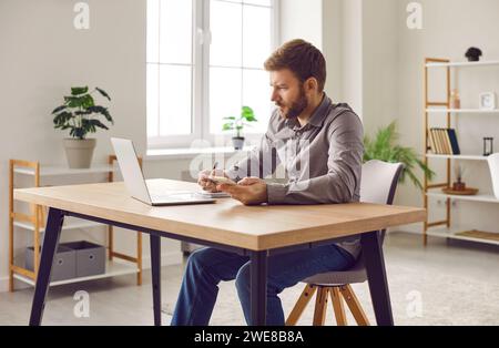 Focused businessman using smartphone and laptop computer at home office Stock Photo