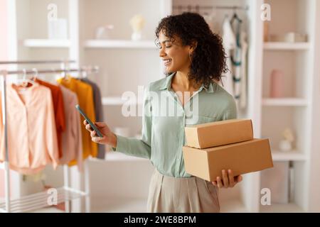 Designer with packages using smartphone in studio Stock Photo