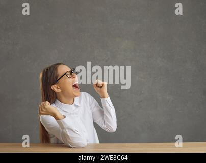Emotional young woman laughs out loud and shouts with clenched fists celebrating victory. Stock Photo