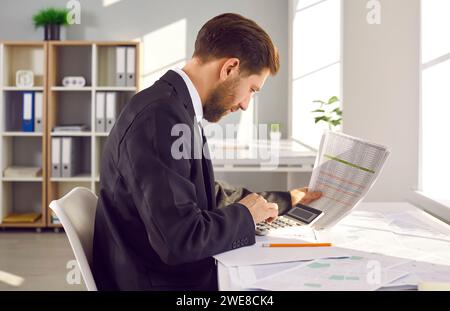 Professional cartographer working with printed cadastral map at table on his workplace. Stock Photo