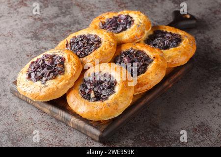 Cebularz lubelski is a round-shaped flatbread topped with diced red onion and poppy seed close-up on a wooden board on the table. Horizontal Stock Photo