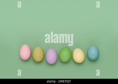 Row of different colored eggs on fun green background. Copy space simple pastel rustic background for traditional Easter holiday card Stock Photo
