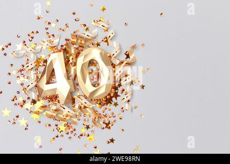 Golden number 40, ribbons and stars confetti on a blue background. Festive composition with copy space. Stock Photo