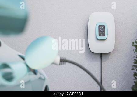 Charging an electric vehicle at home with a home charging station (wallbox). Focus on the wallbox displaying status information. Selective focus. Stock Photo