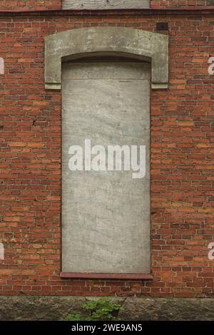 Old boarded up window on a red face brick building. Stock Photo