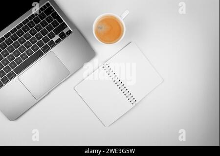 Top view of grey laptop computer on white background. Notebook and coffee cup flat lay, copy space. Stock Photo