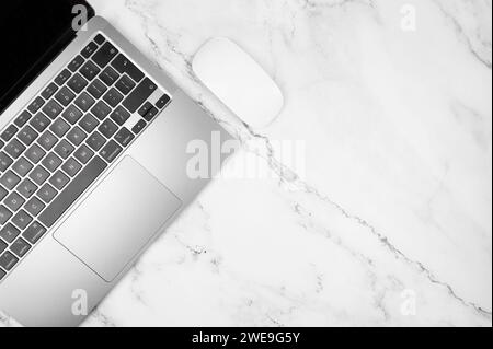 Top view of grey laptop computer on white marble background. Office table lat lay, copy space. Stock Photo