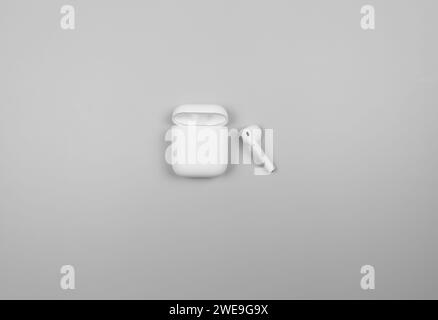 Top view of white earphones case on light grey background. Modern office flat lay, copy space. Stock Photo