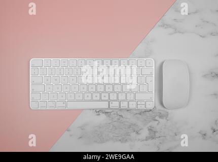Top view of white keyboard, mouse on pink and white marble background. Modern office flat lay, copy space. Stock Photo