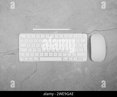 Top view of white keyboard, mouse and pen on concrete background. Modern office flat lay, copy space. Stock Photo