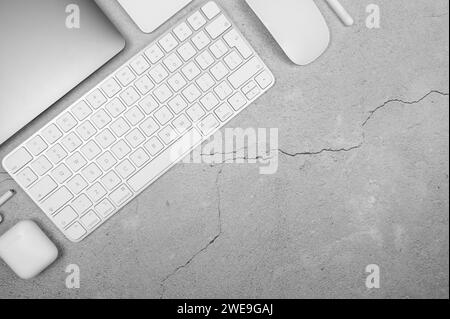 Top view of laptop computer, white keyboard, mouse, touchpad, earphones case, pen on concrete background. Modern office flat lay, copy space. Stock Photo