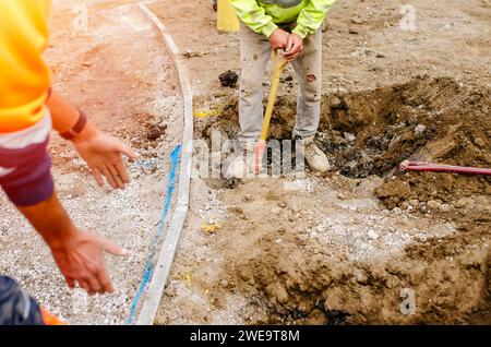 A new footpath is under construction as builders bring stone, levelling and compacting it Stock Photo