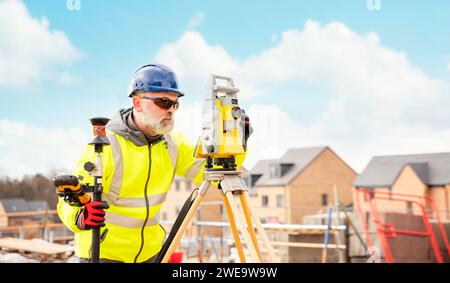 Surveyor builder site engineer with theodolite total station at construction site outdoors during surveying work Stock Photo