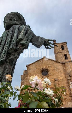 En Alcántara, imagen desde atrás de la estatua de bronce de San Pedro de Alcántara como tocando  con su mano la torre de la iglesia, Cáceres, España Stock Photo